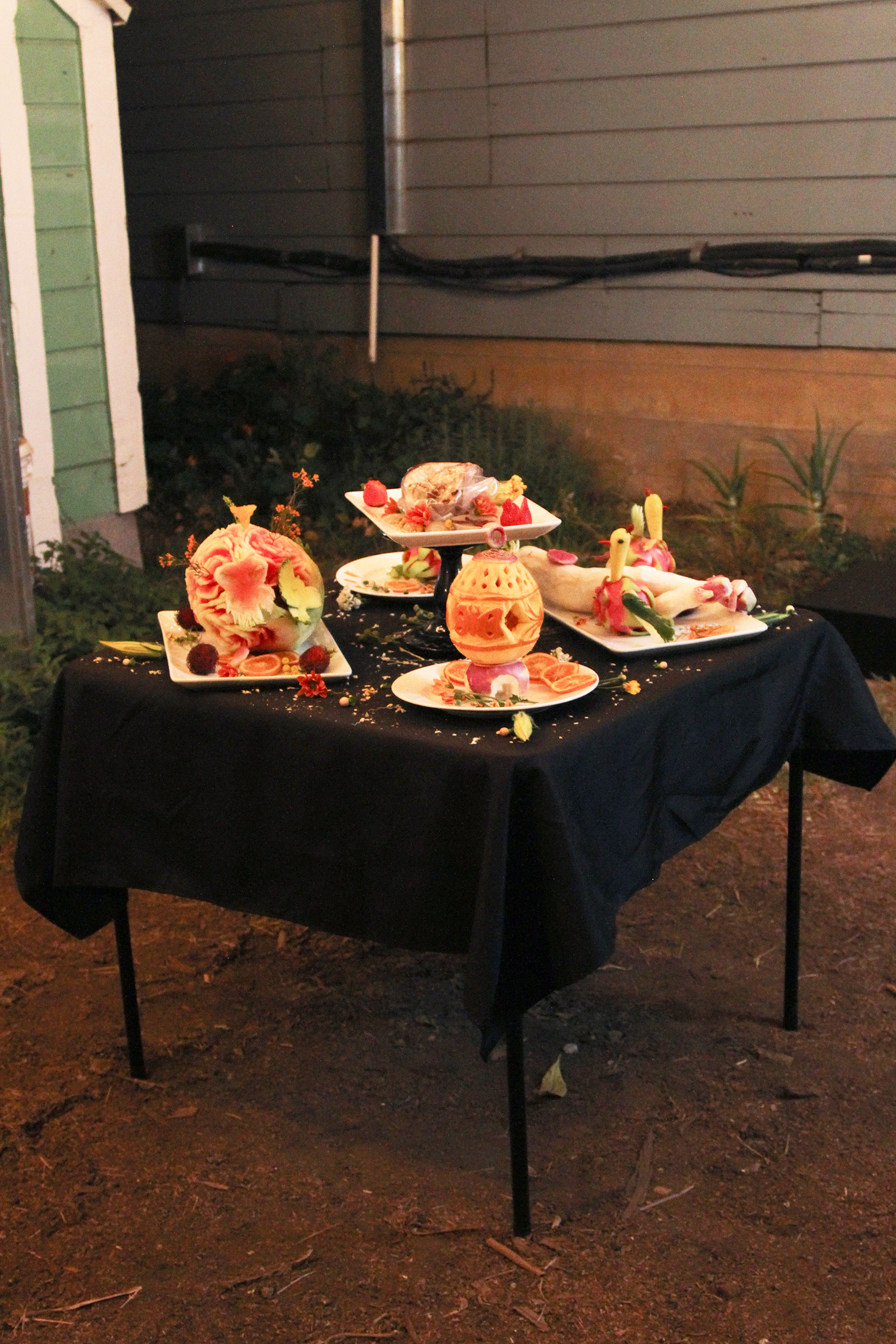 Table of food sculptures outside in a backyard at night